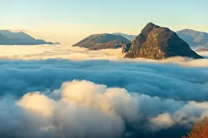 Lugano Prints: Mountain Peak San Salvatore Above Cloudscape with a Autumn Tree and Sunlight with Clear Sky in Lugano