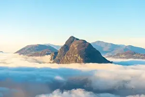 Lugano Prints: Mountain Peak San Salvatore Above Cloudscape with Sunlight and Clear Sky in Lugano