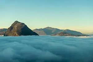 Lugano Prints: Mountain Peak San Salvatore Above Cloudscape with Sunlight and Clear Sky in Lugano