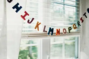 Blinds Prints: Multi colored alphabet decoration hanging on string by window at home