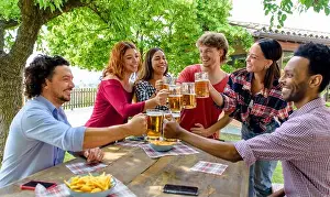 Booze Prints: multiethic group of people enjoying beer together outdoor sitting on a garden table