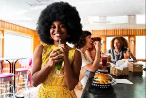 Enjoying Prints: Multiethnic group of young happy friends bonding at vintage diner burger house restaurant - young woman smiling