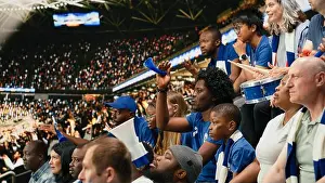 Silence Prints: Multigenerational soccer fans watching tense moment from crowded stadium stands