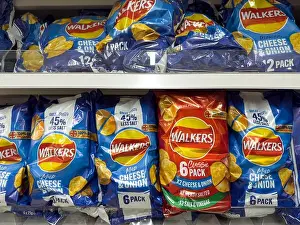 Grocery Store Prints: Multiple 5-pack bags of Walkers crisps in assorted flavours are stacked neatly on a supermarket shelf for sale
