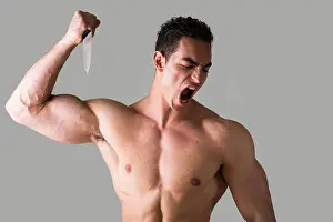 Bodybuilder Prints: Muscular young man holding big knife ready to stab and screaming
