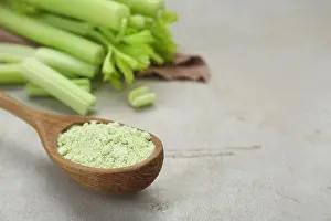 Tasty Prints: Natural celery powder in wooden spoon on grey table, closeup. Space for text