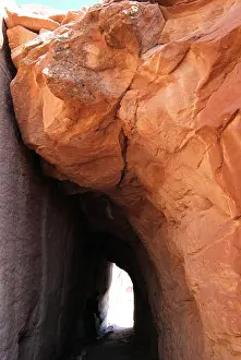 Navajo Prints: Natural red sandstone tunnel in Vermillion Cliffs National Monument that evokes an illuminated bright white door after