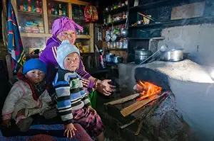 Nepal Prints: Nepali woman with her 2 children sitting at the fireplace in their kitchen