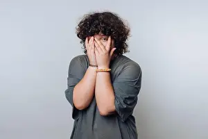 Curly Hair Prints: In a neutral background, an individual with curly hair conceals their face with their hands
