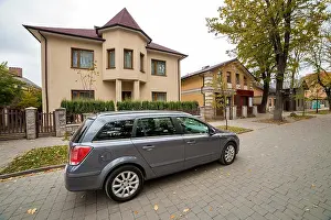 Owner Prints: New expensive gray car parked in paved parking lot in front of big two story cottage