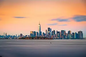 New York, New York, USA skyline from the harbor with Ellis Island at dusk
