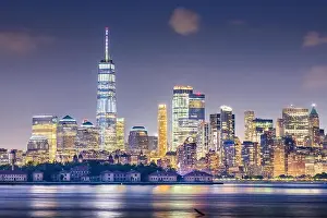 New York, New York, USA skyline from the harbor with Ellis Island at night