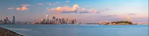 New York, New York, USA skyline from the harbor with Ellis Island and the Statue of Liberty at dusk