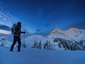 Images Dated 14th January 2023: Night photo climber stands on top of a mountain in the snow and looks at the surrounding mountains