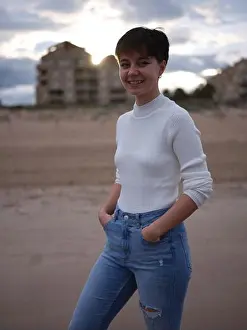 Femininity Prints: non-binary person posing smiling on the beach with hands in pockets