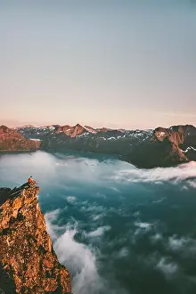 Norway vacations travel man sitting on the edge cliff mountains above sea alone adventure lifestyle weekend trip getaway