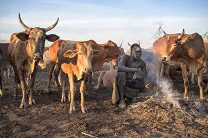 Gathering Prints: Nuba herder covered in ash squatting by smoke