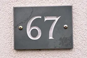 Numeral Prints: The number sixty seven carved into a slate tile plaque on a home to show the properties address
