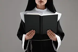 Sister Prints: Nun reading Bible on grey background, closeup