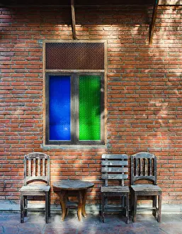 Holiday Home Prints: Old asian styles wooden tables and chairs are set infront of old vintage grungy red brick wall with blue