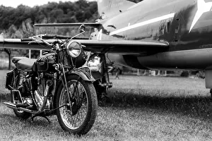 Aged Prints: Old, black motorcycle made by Triumph Motorcycles - british brand with an airplane in the background