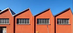 Shed Prints: Old-fashioned factory shed with a deep orange facade on a blue sky