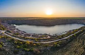 Old Europe Prints: Old flooded stone quarry with large stones in the evening warm bright light covered with small dry plants