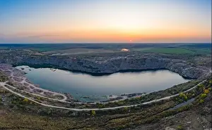 Old Green Prints: Old flooded stone quarry with large stones in the evening warm bright light covered with small dry plants