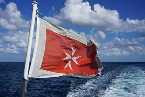 Stern Prints: Old Maltese flag. White cross on red background flying at stern of ship travelling in the Mediterranean Sea