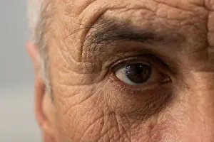 Eyelid Prints: Old man face with wrinkles, grey haired pensioner ageing skin close up