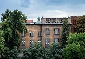 Old and rustic apartment house with many windows and lush trees in Krakow, Poland