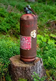 Desolate Prints: old and rusty fire extinguisher on a tree stump in a forest, Austria