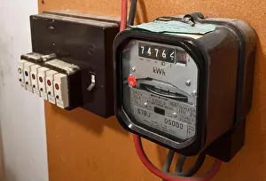 An old style mechanical electricity meter alongside a row of plug in fuses