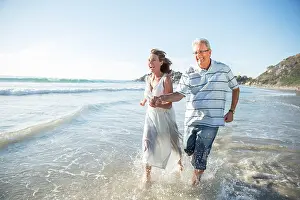 Jolly Prints: Older couple playing in waves on beach