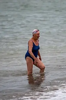 older lady walking out of the sea after wild cold water swimming in the solent