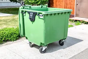 Throw Prints: Opened green plastic garbage container at the sunny city street in summer