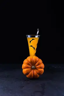 Squash Prints: Orange pumpkin and pumpkin non-alcoholic mocktail in tall glass decorated with paper bats