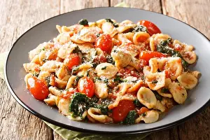Served Prints: orecchiette pasta with spinach in tomato sauce sprinkled with parmesan closeup in a plate on a table