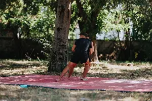 Wrestling Prints: Outdoor wrestling match on a red mat beneath a tree, two men grappling with intense focus