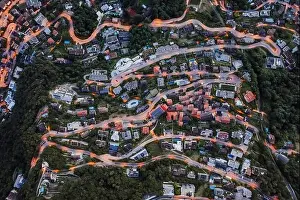 Overhead aerial drone shot view of winding mountain road street light on Monte Bre in Lugano, Switzerland