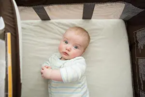 Mattress Prints: Overhead portrait of cute baby boy lying on mattress in pack n play at home