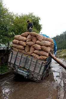 Bhutan Prints: Overloaded truck stuck on wet dirt road