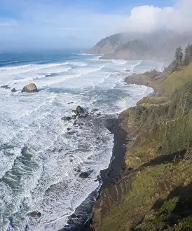 The Pacific Ocean washes against the rocky coastline of northern Oregon. This beautiful, wild region is often covered by a dark foggy marine layer