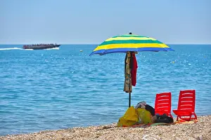 Pair of sun loungers and a beach umbrella on a deserted beach; perfect vacation concept