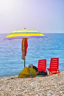 Pair of sun loungers and a beach umbrella on a deserted beach; perfect vacation concept