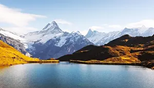 Panorama of Bachalpsee lake in Swiss Alps mountains on sunset. Snowy peaks of Wetterhorn, Mittelhorn and Rosenhorn on background
