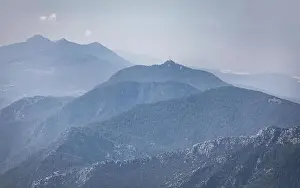 Panorama of beautiful silhouette mountains in blue tones with haze and clouds