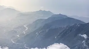Panorama of beautiful silhouette mountains in blue tones with haze and clouds
