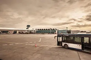 Panorama of Bucharest Henri Coanda Otopeni Airport shows an apron bus beside a parked aircraft