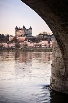 Panorama of Saumur skyline under a bridge arch with medieval castle and churches
